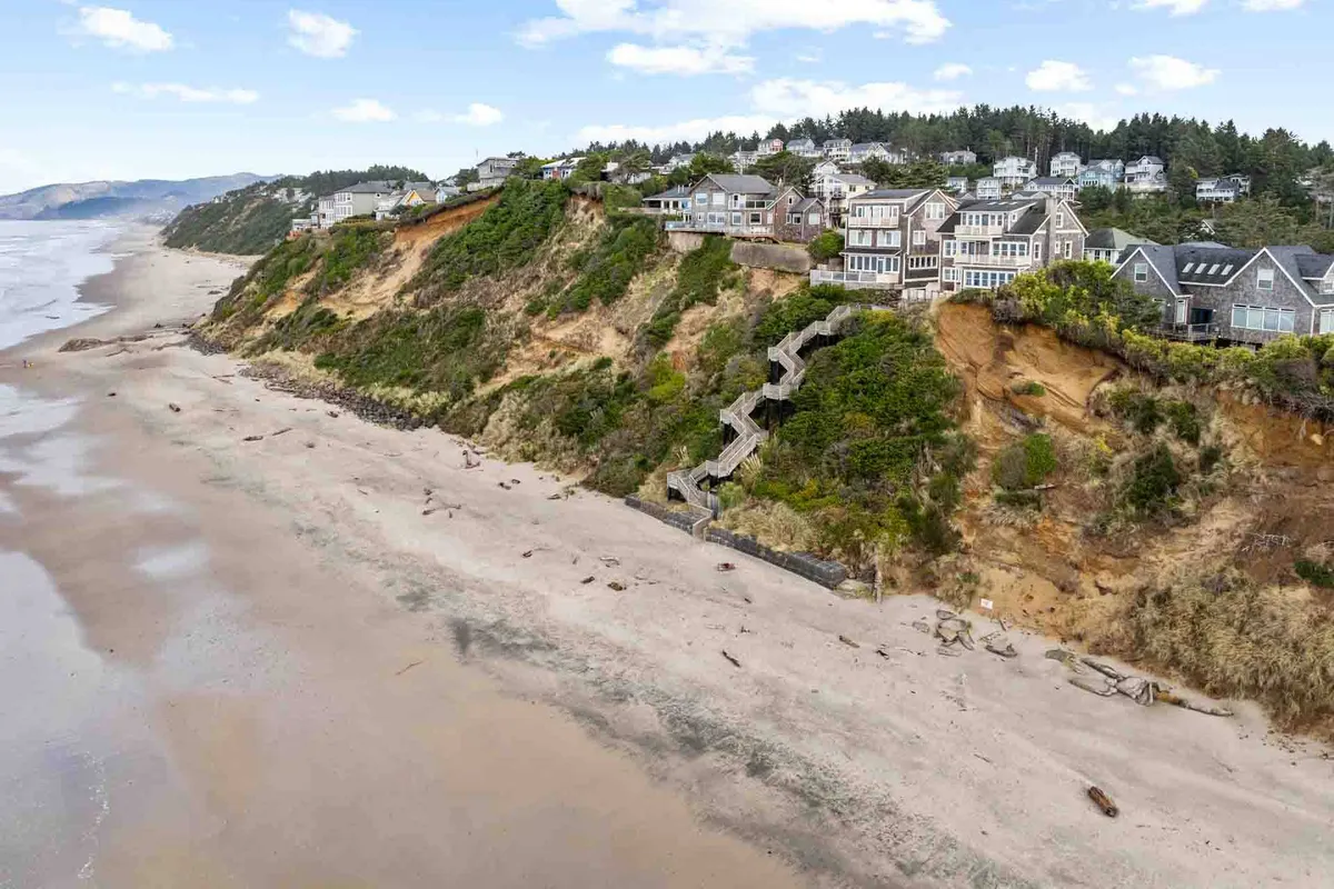 An inviting exterior view of cliffside homes overlooking the beach, with a staircase leading directly down to the shore. The image captures both the beauty of the coastline and the easy access to beach activities like tidepooling, walking, and exploring.