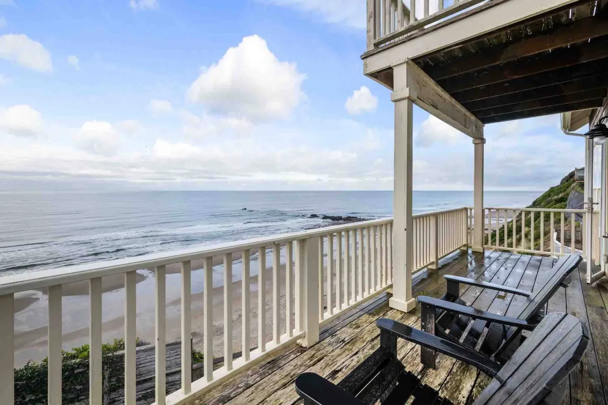 A tranquil exterior deck furnished for comfort, with unobstructed views of the ocean and sky. The clouds and soft lighting suggest the beauty of the coast in every season, ideal for sunrise coffee or evening stargazing.