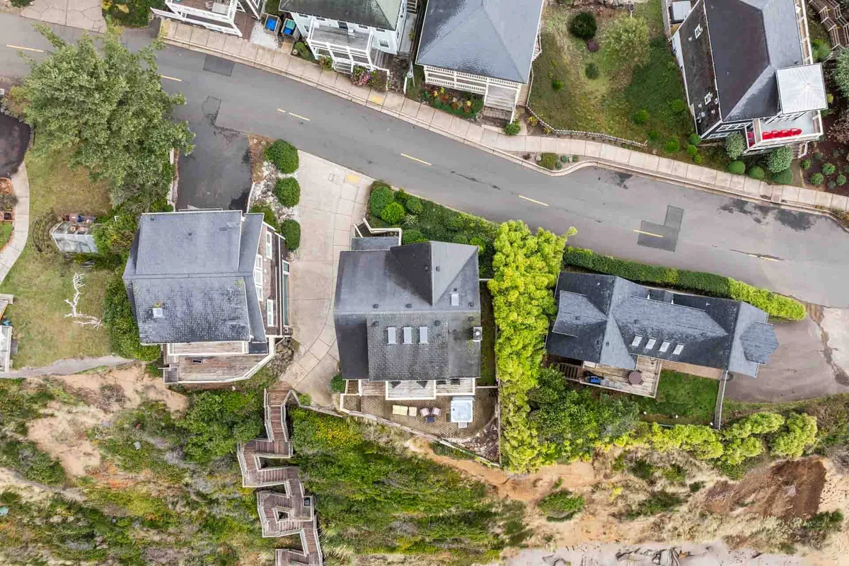 A relaxed neighborhood streetscape with residential buildings, a treeline, and a path along the cliffside, suggesting a walkable, community-oriented environment. The scene hints at sunset views and opportunities for group strolls or outdoor activities.