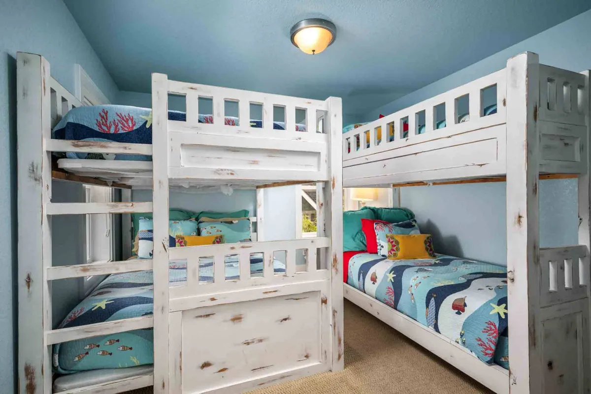 A cheerful bunk room with colorful bedding and bunk beds, illuminated by soft lighting. The playful design is inviting for younger guests and encourages imaginative play and relaxation.